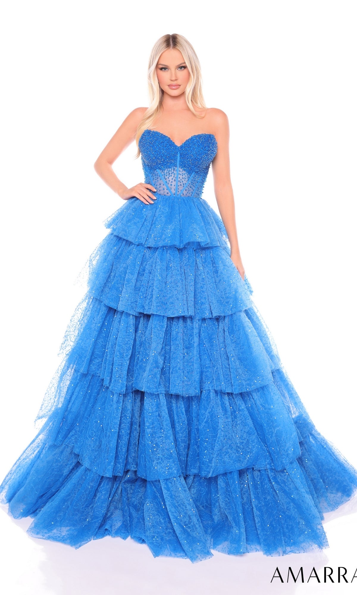 A woman wears the Long Formal Dress 88131 by Amarra, a strapless ballgown featuring a fitted bodice and a full, layered blue tulle skirt for an enchanting ruffle effect.